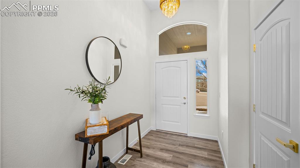 Foyer with wood finished floors and hanging lights