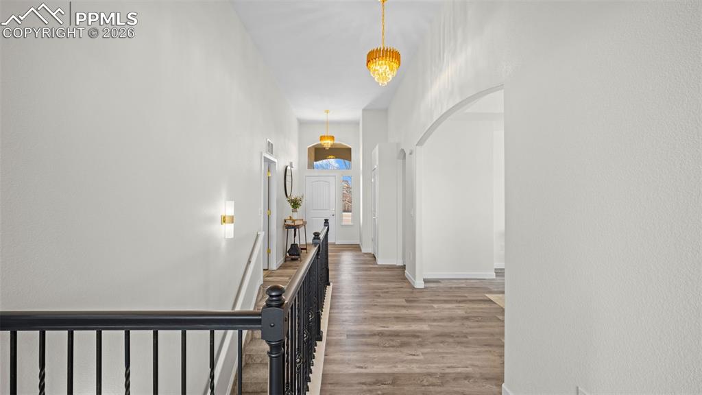 Corridor featuring arched walkways, an upstairs landing, and light wood-style flooring