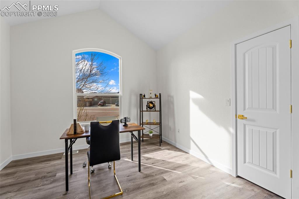 Office with lofted ceiling and wood finished floors