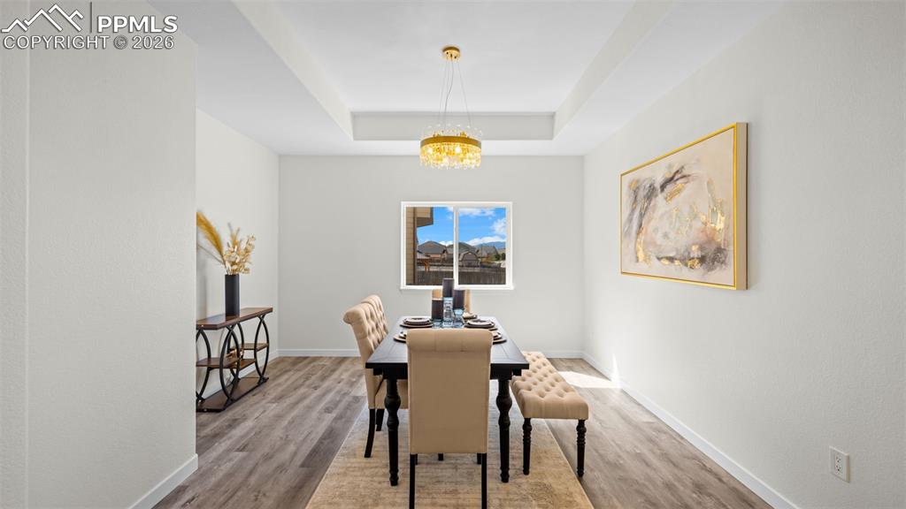 Dining room featuring light wood-style flooring, a tray ceiling, and a chandelier