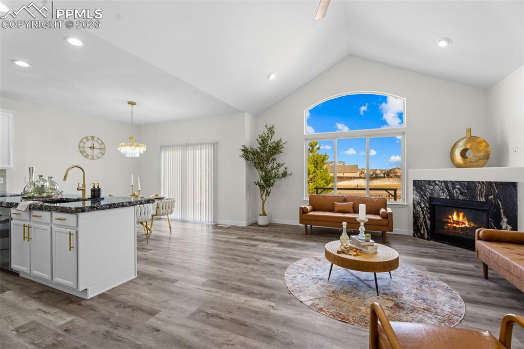 Living room with a fireplace, dark wood-style flooring, and a chandelier
