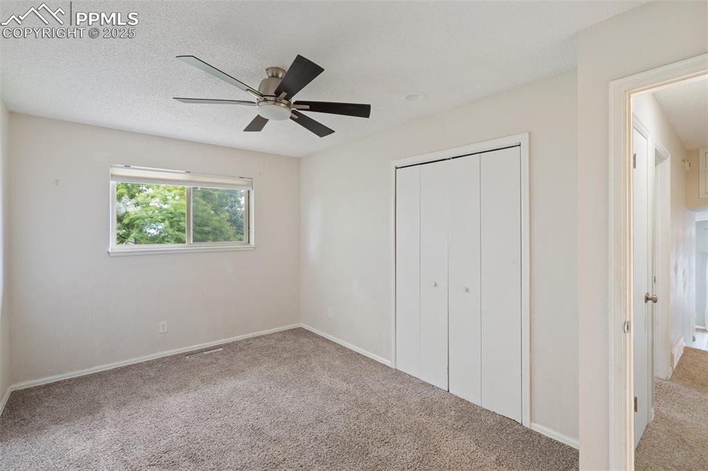 Bedroom featuring a closet, carpet, ceiling fan, and a textured ceiling