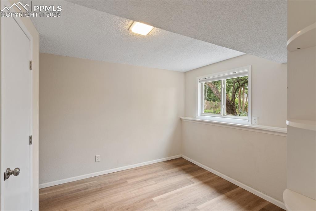 Bedroom with light wood finished floors, a closet, an ensuite, and a textured ceiling