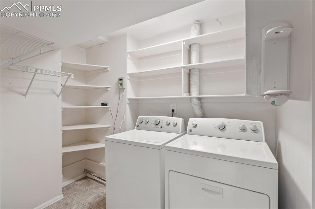 Laundry room with washer and clothes dryer and light tile patterned floors