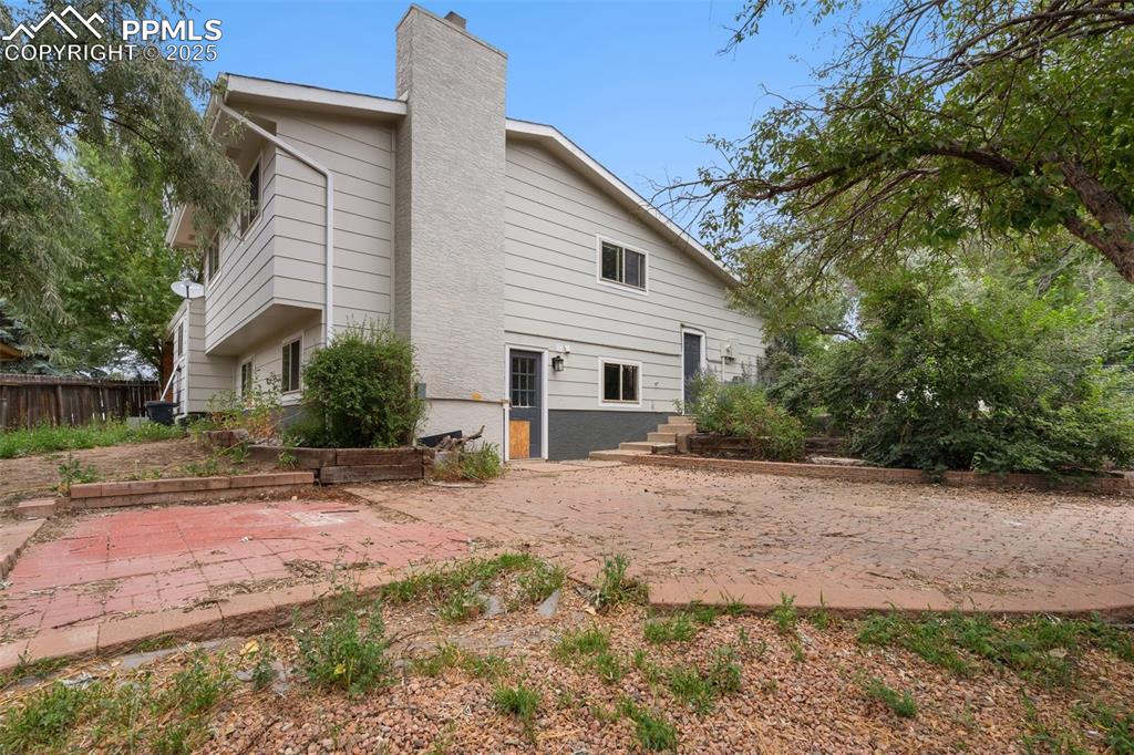 Rear view of house with a chimney and a brick patio area