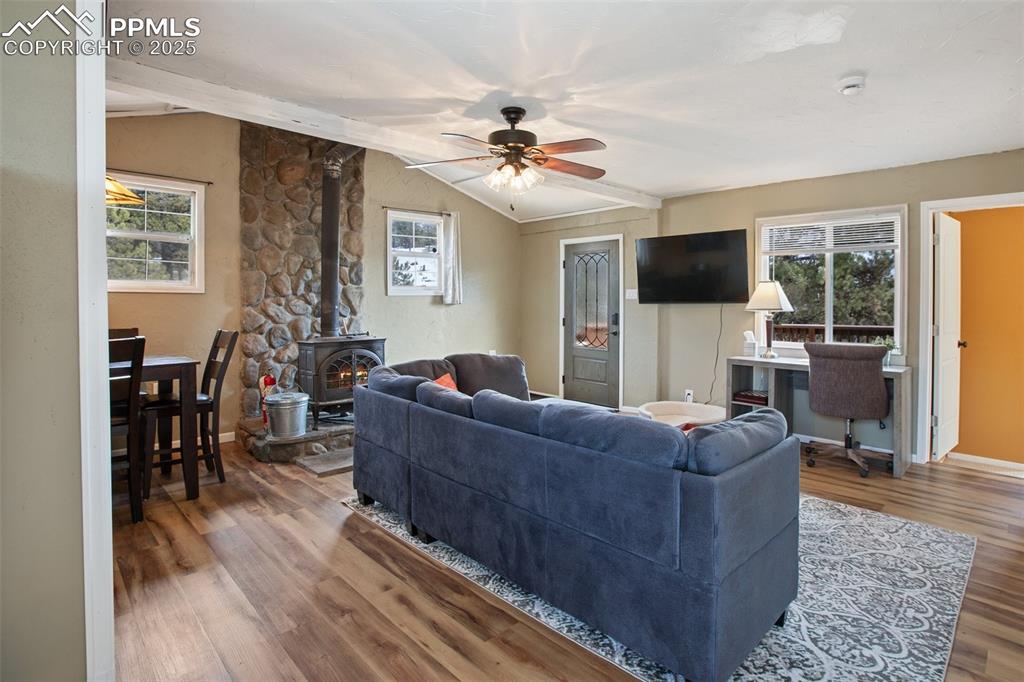 Living room featuring a wood stove, wood finished floors, and a ceiling fan