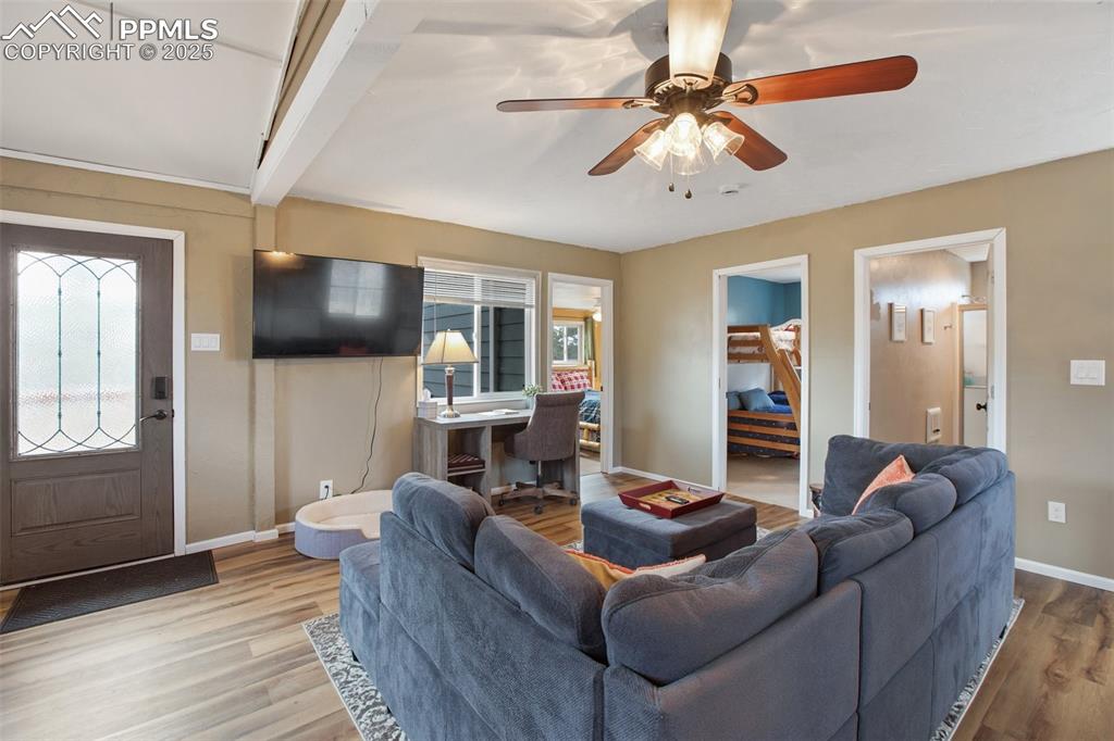 Living area with wood finished floors, plenty of natural light, a ceiling fan, and beam ceiling