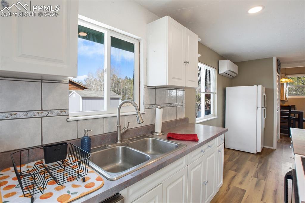 Kitchen featuring freestanding refrigerator, white cabinets, decorative backsplash, stove, and recessed lighting