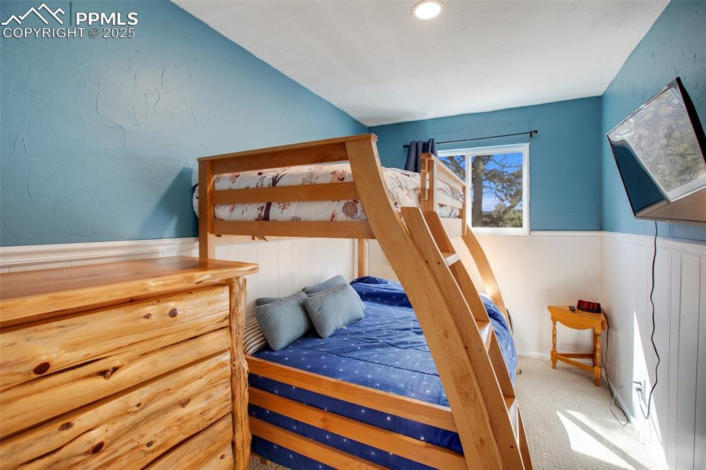 Carpeted bedroom featuring wainscoting and a textured wall