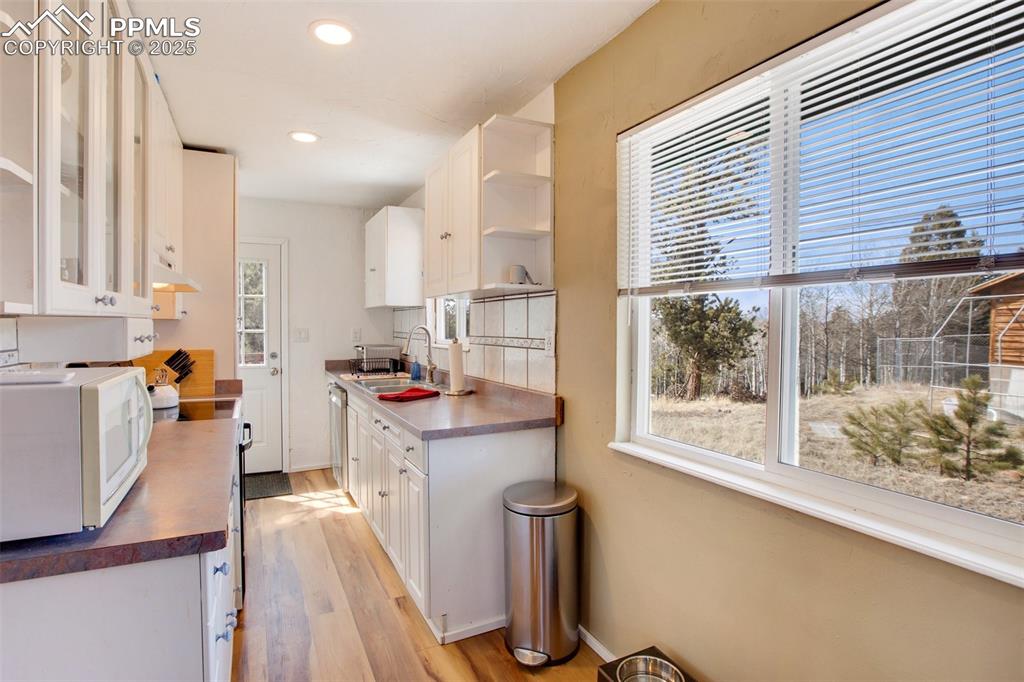 Kitchen featuring white cabinetry, white appliances, dark countertops, light wood-type flooring, and open shelves