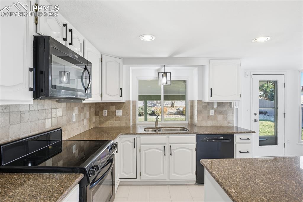 Kitchen featuring black appliances, dark stone countertops, decorative backsplash, white cabinets, and recessed lighting