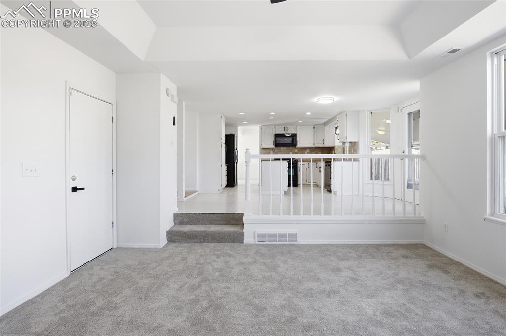 Unfurnished living room with light carpet and stairway