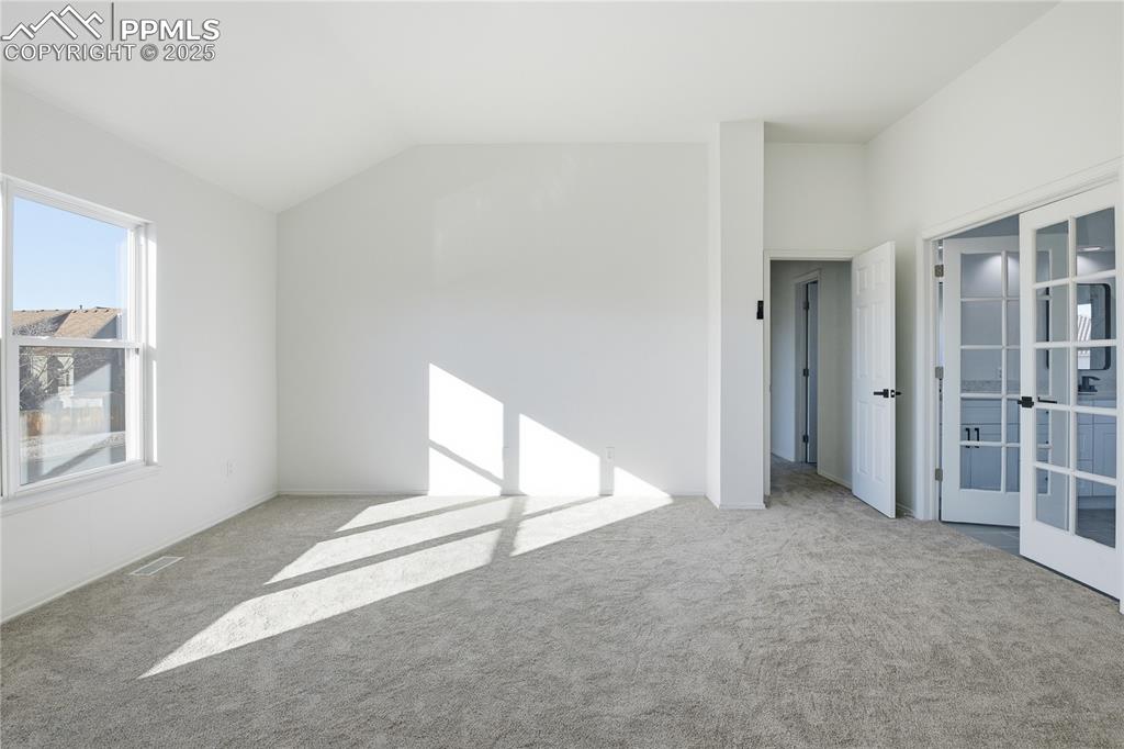 Spare room with lofted ceiling, carpet floors, and french doors