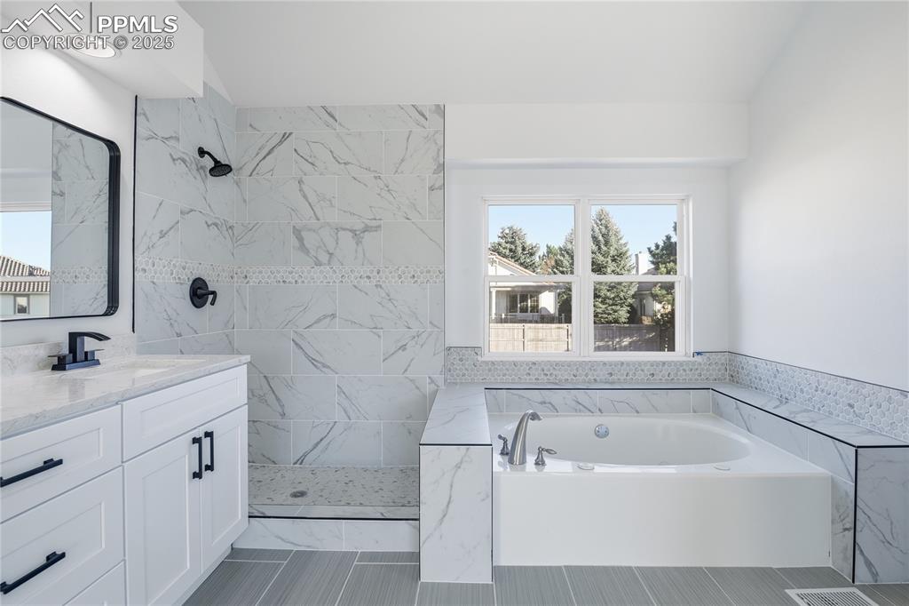 Bathroom featuring vanity, a bath, and a marble finish shower