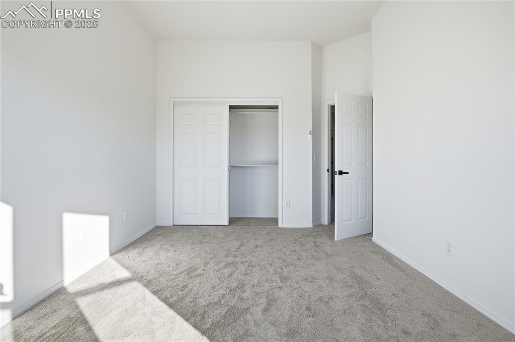 Unfurnished bedroom with light carpet and a closet