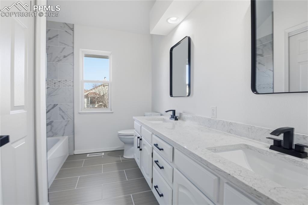 Full bath featuring double vanity and tub / shower combination