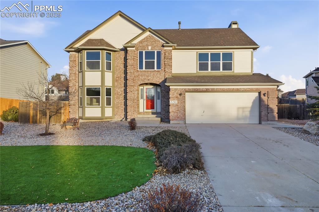 View of front of home featuring concrete driveway, an attached garage, a shingled roof, and brick siding