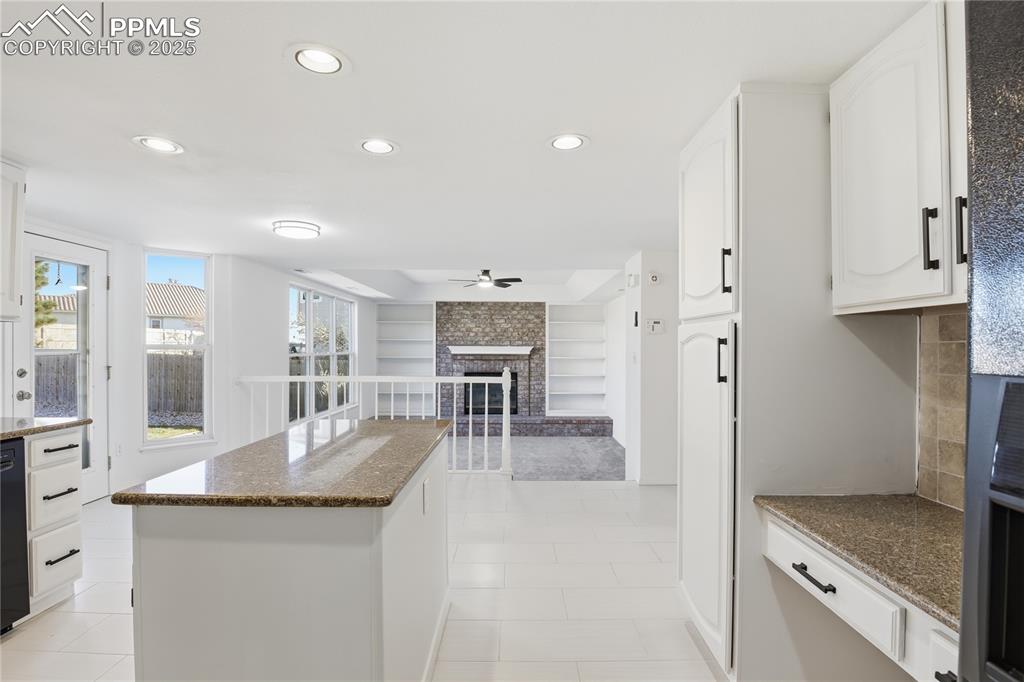 Kitchen featuring a fireplace, white cabinetry, recessed lighting, dark stone counters, and open floor plan