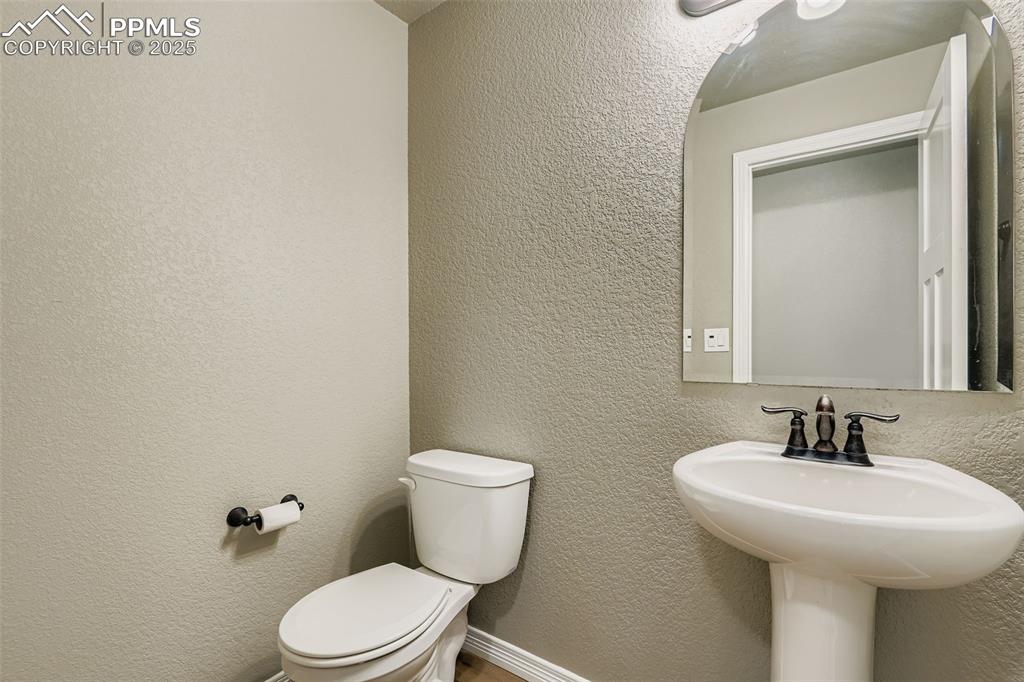 Half bathroom featuring a textured wall and toilet