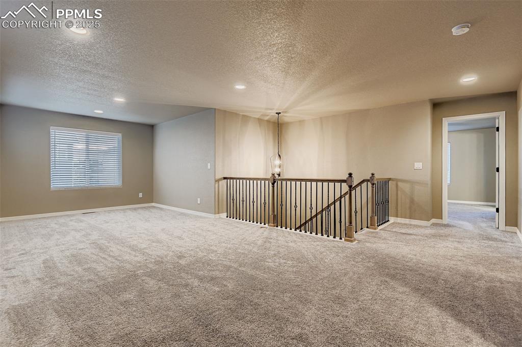 Spare room with a textured ceiling, carpet, recessed lighting, and a chandelier