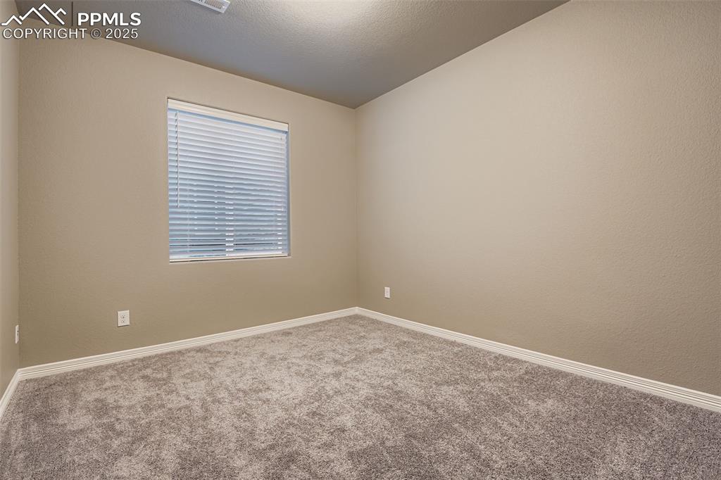 Carpeted spare room featuring baseboards and a textured ceiling