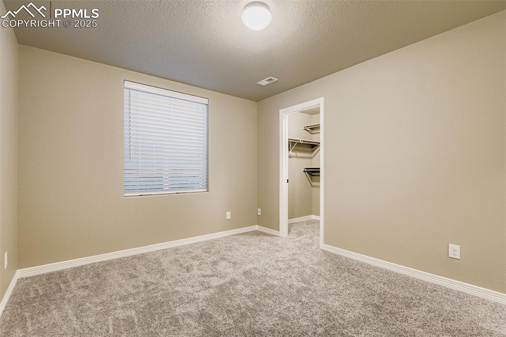 Empty room with light carpet and a textured ceiling