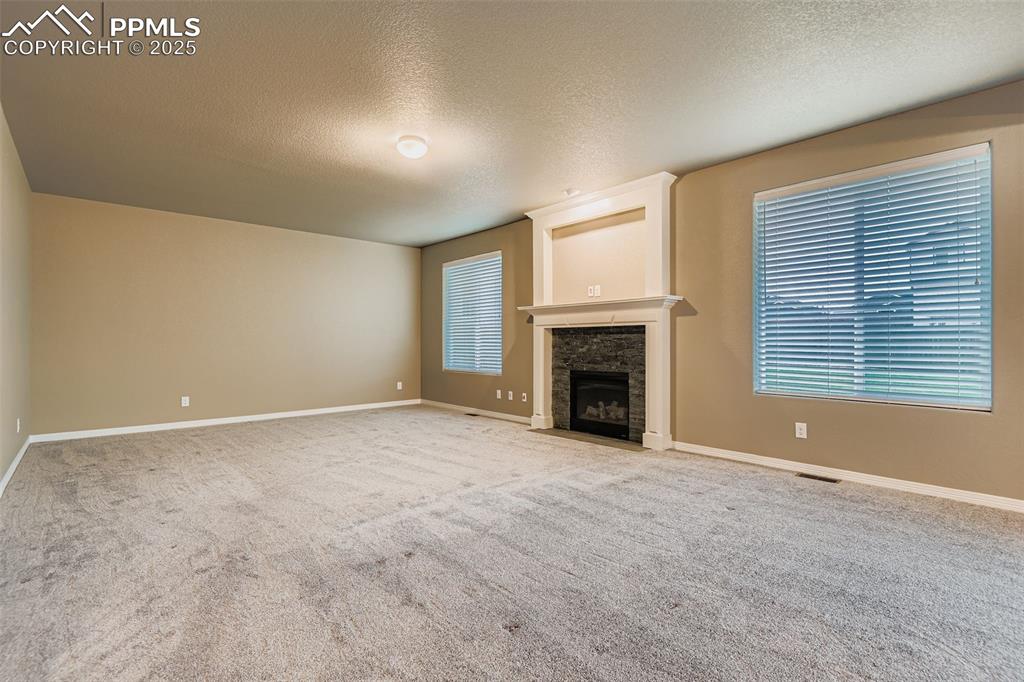 Unfurnished living room with a textured ceiling, a fireplace, and carpet flooring