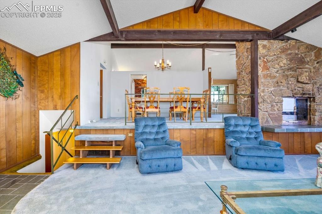 Living room featuring wooden walls, a textured ceiling, a fireplace, and a chandelier