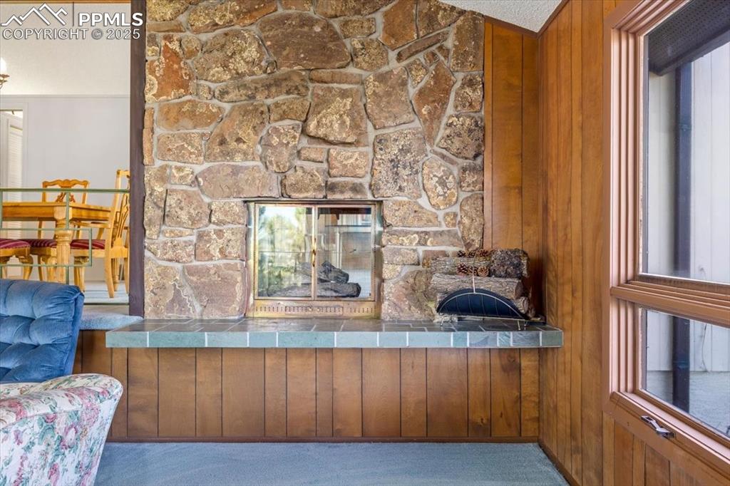 Detailed view of a stone fireplace, carpet, and wood walls