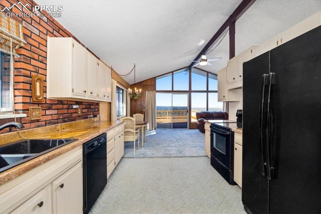 Kitchen with black appliances, light carpet, a textured ceiling, a chandelier, and light countertops