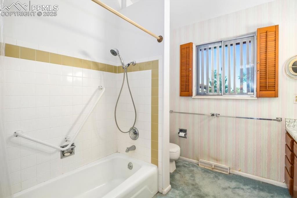 Bathroom featuring wallpapered walls, shower / tub combination, and vanity