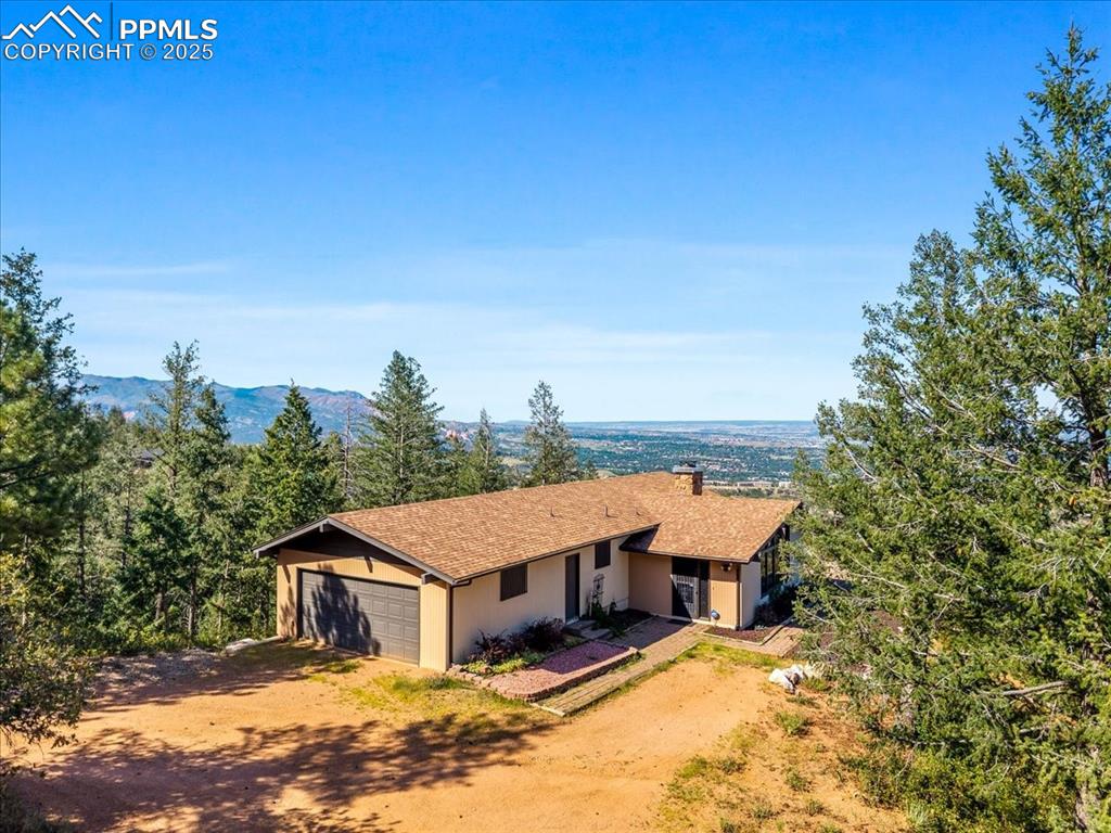 Ranch-style house featuring a chimney, stucco siding, driveway, covered porch, and a garage