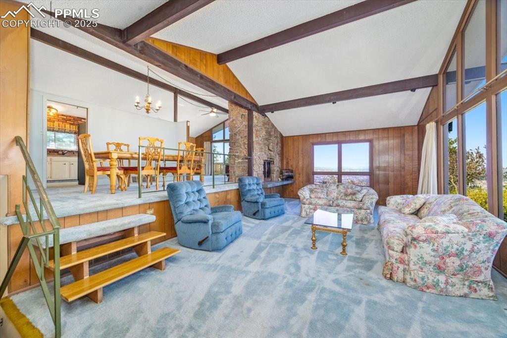 Living room with plenty of natural light, wooden walls, and carpet flooring