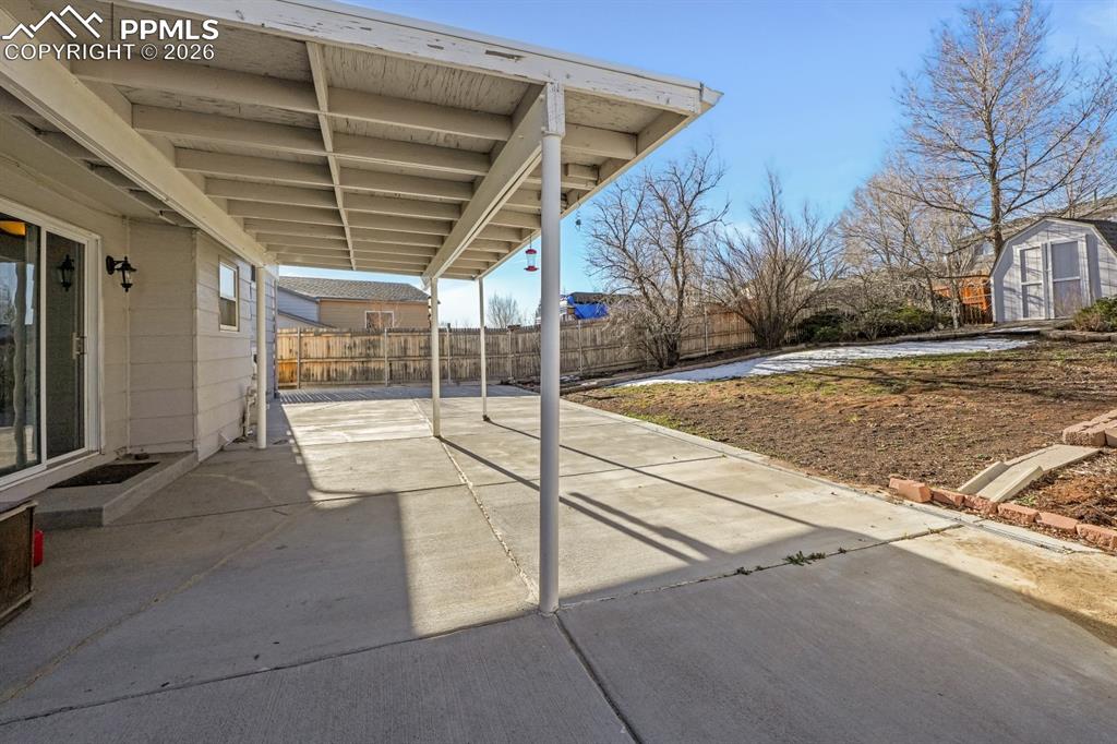 Fenced backyard featuring a patio area and a shed