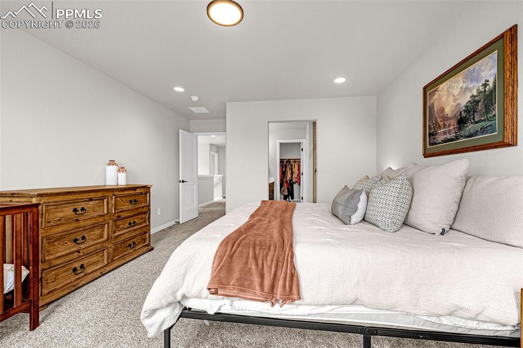 Huge primary bedroom on the upper level featuring fresh clean carpet, recessed lighting, large bright windows, and an ensuite primary bathroom 