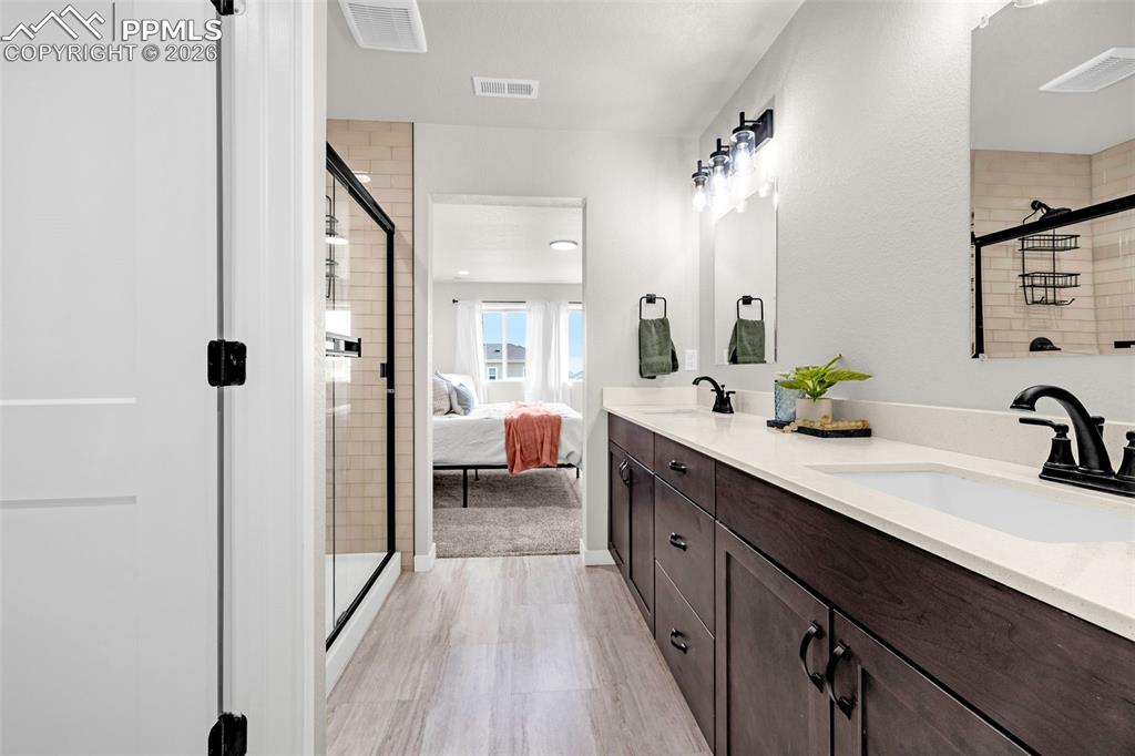 Primary bathroom with a beautiful walk-in shower, double vanity, a walk in closet, and luxury tile flooring 