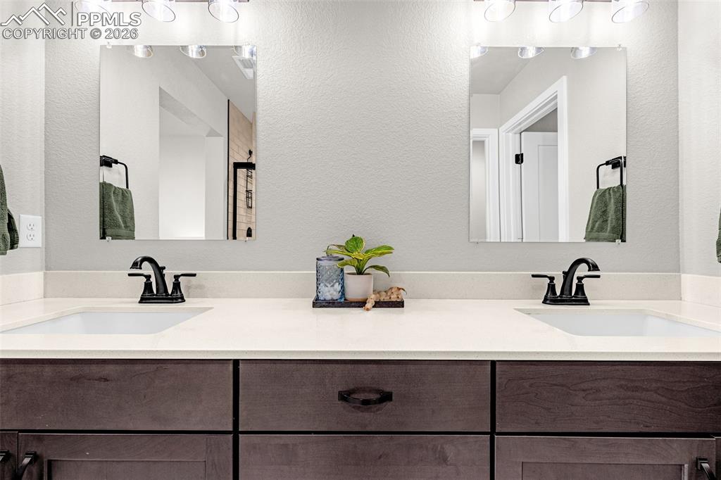 Primary bathroom with a beautiful walk-in shower, double vanity, a walk in closet, and luxury tile flooring 