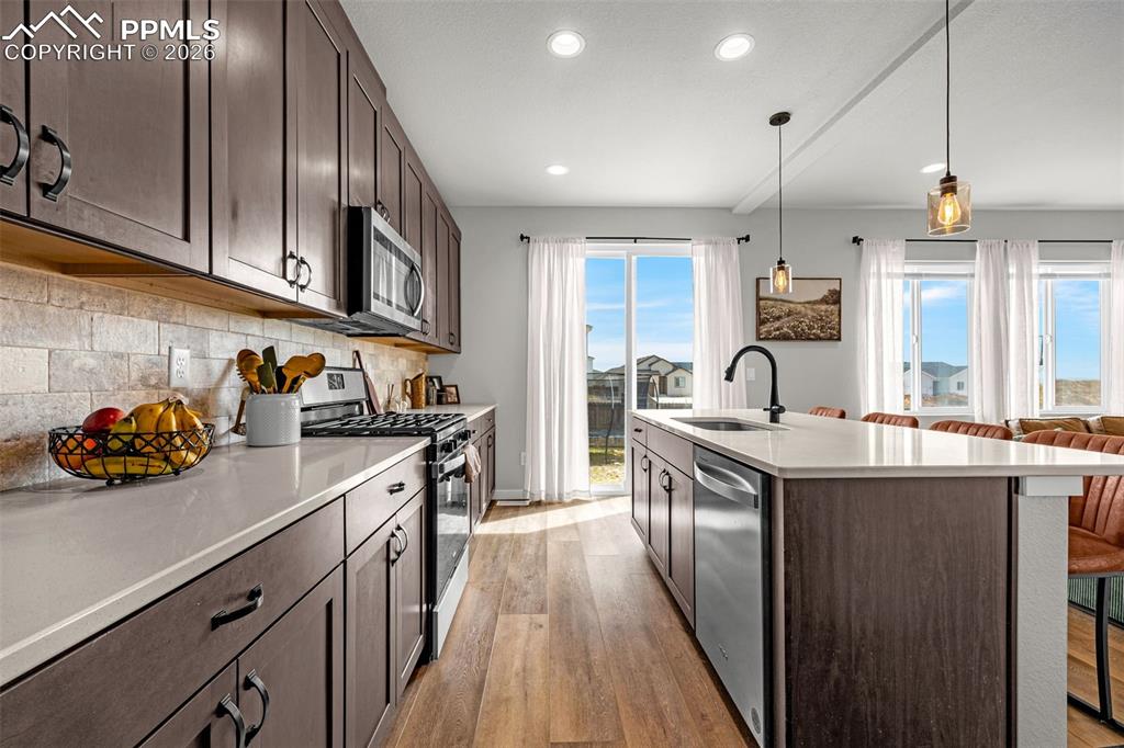 Kitchen featuring stainless steel appliances, dark espresso finished cabinetry, a center island, luxury vinyl plank flooring and walk out to back yard