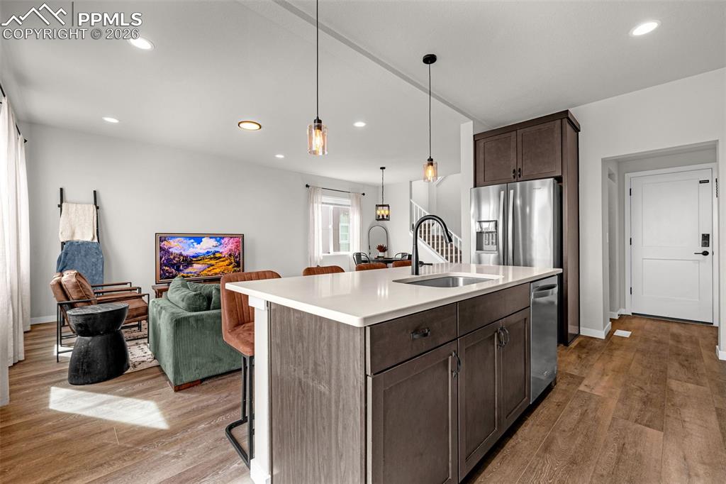 Kitchen featuring stainless steel appliances, dark espresso finished cabinetry, a center island, and luxury vinyl plank flooring