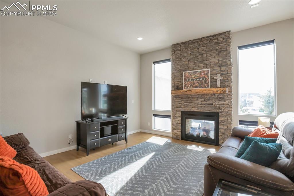 Living room with real white oak floors, plenty of natural light, a stone double sided indoor/outdoor fireplace, and recessed lighting