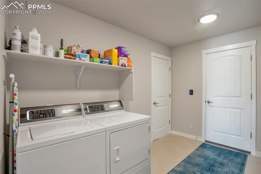 Laundry area Main Level with light tile flooring. Custom made coat rack and storage to the right in this photo. The door on the right would enter the garage. Door on the left would lead to the main entrance of the home. There is a door behind the camera that leads to the Main Level Master Bedroom #1.
