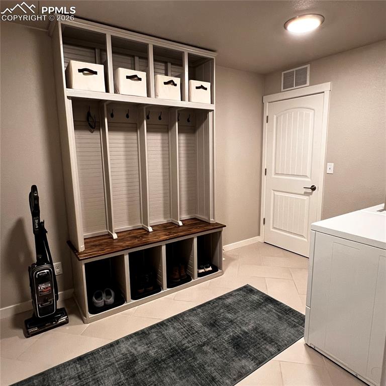 Mudroom/Laundry Room, storage included with home, door on left not pictured goes to garage, door in pic goes towards Primary Bedroom #1 Main level, room features light tile patterned floors