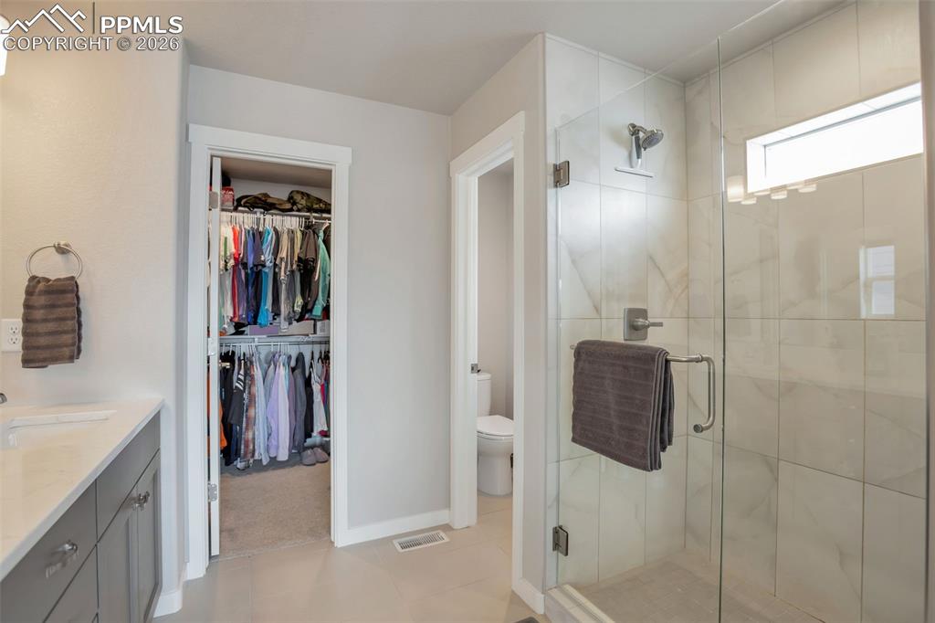 Primary Full bathroom #1 featuring vanity, a spacious walk-in closet, closeted toilet and a stall shower