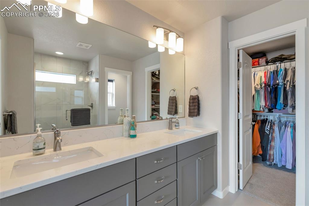 Primary Full bathroom  #1 featuring a walk in closet, a stall shower, closeted toilet and double vanity