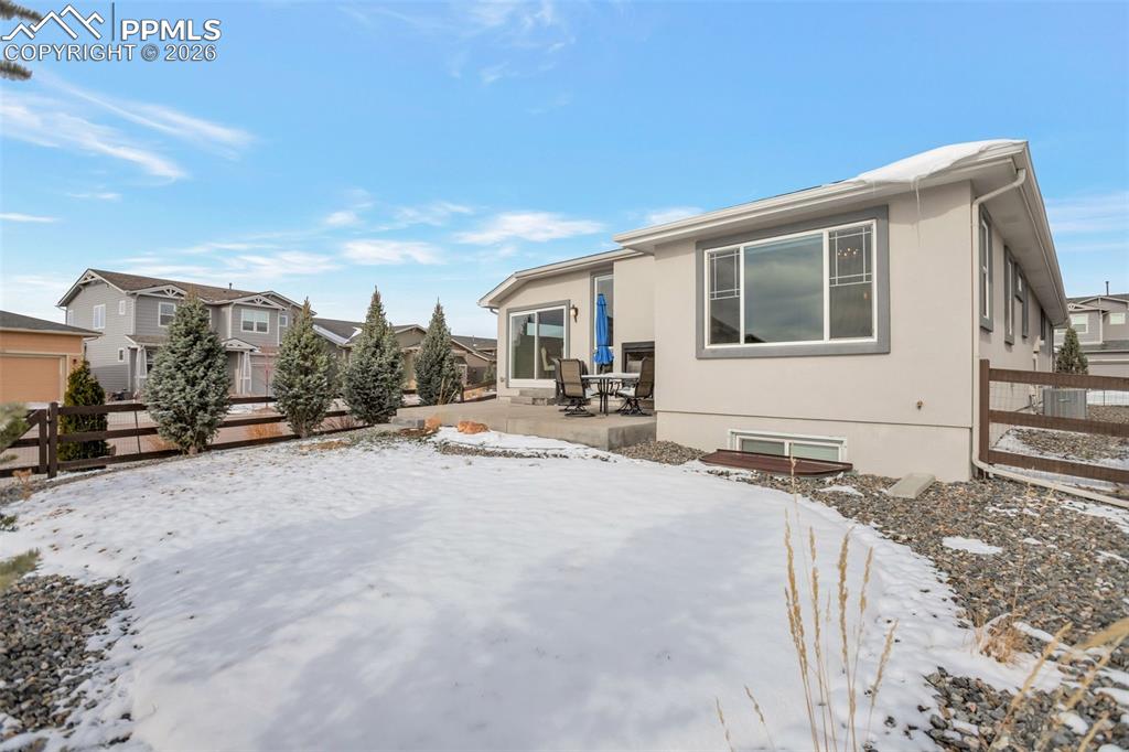 Rear of property with fully fenced yard, gate on the left to green space that also has the mailbox, fireplace on back patio area and stucco siding