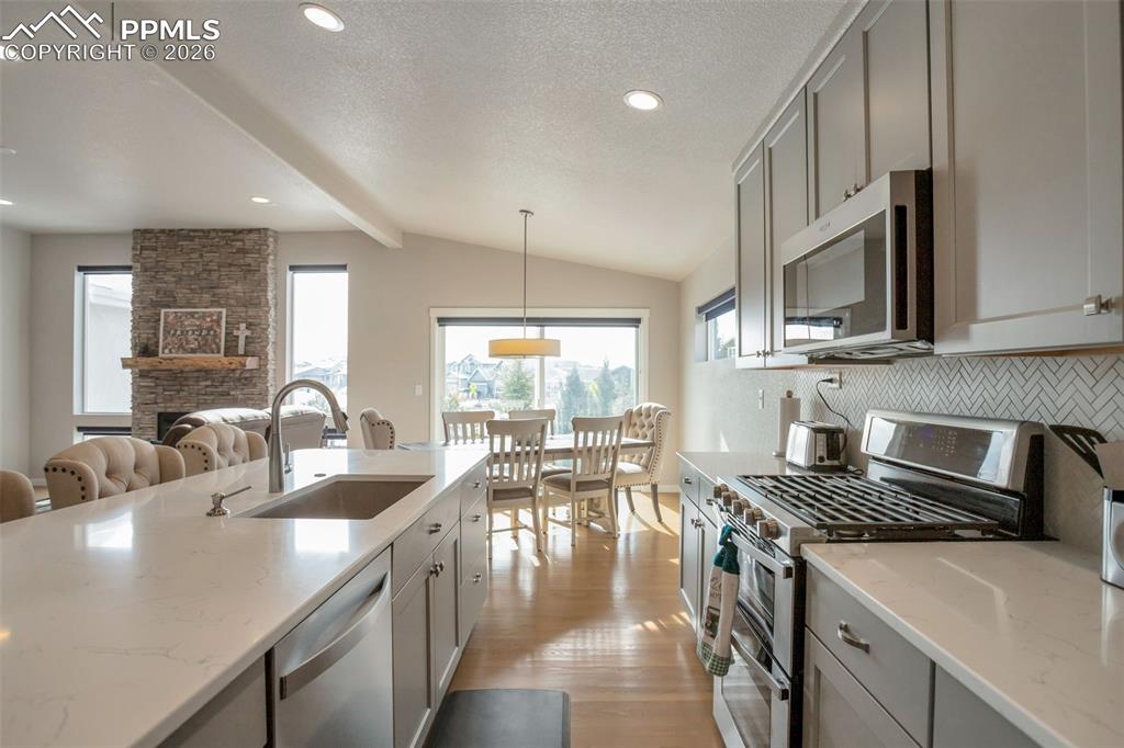 Kitchen featuring stainless steel appliances, gray cabinetry, quartz counters, large island, and white oak wood finished floors