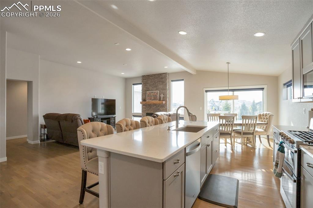 Kitchen with open floor plan, stainless steel appliances, an island with sink, and quartz counters