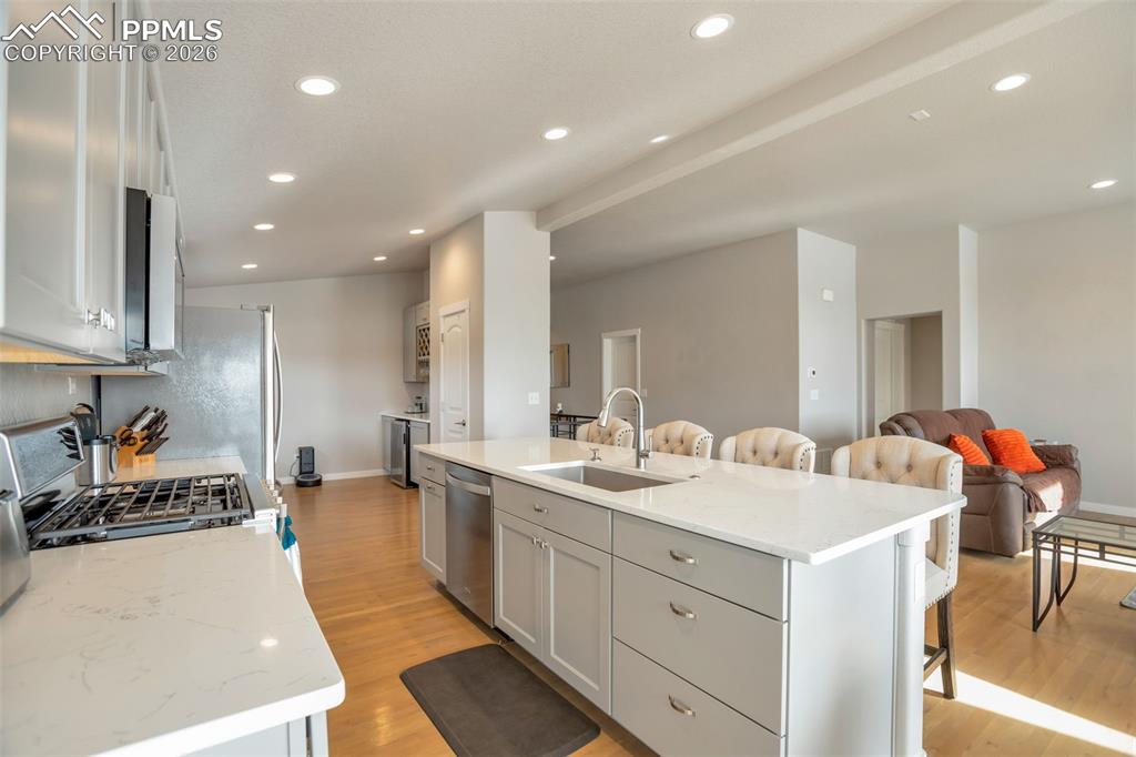 Kitchen featuring a breakfast bar, stainless steel appliances, open floor plan, quartz countertops, and recessed lighting