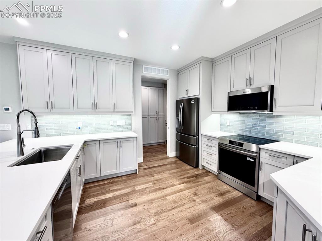 Full-sized Gourmet Kitchen with Quartz Countertops, Upper Cabinets to the Ceiling, Under-cabinet lighting., Induction Range, Included Stainless Still Fridge, and Wood Flooring.