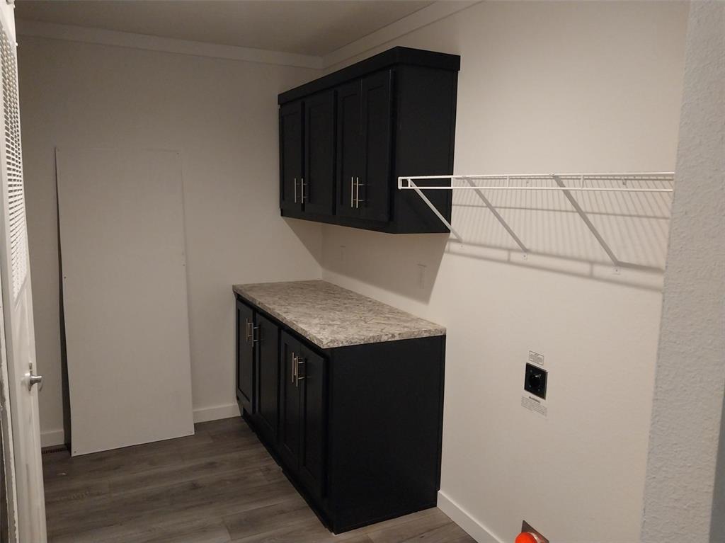 Laundry room with dark wood-style floors, cabinet space, and ornamental molding